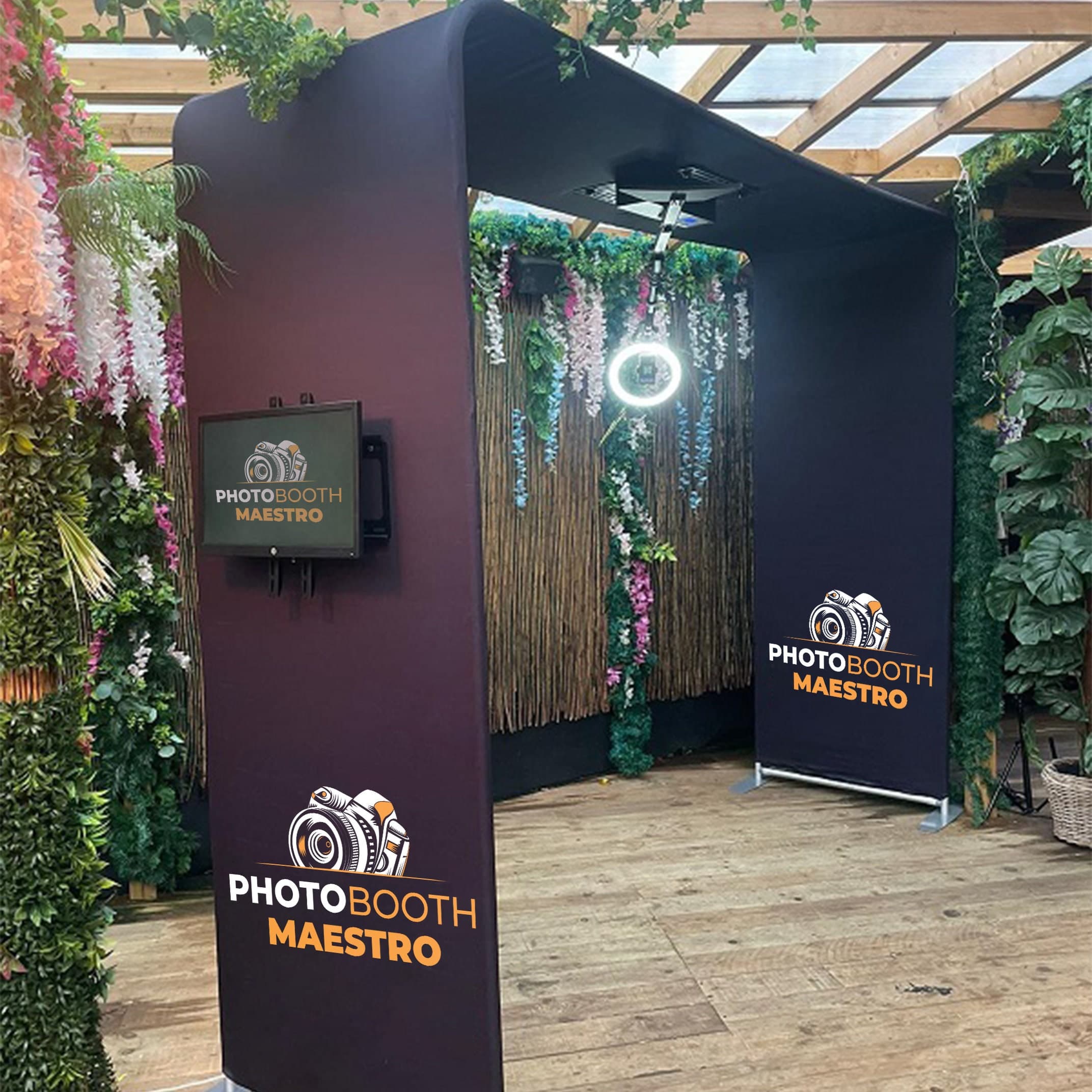 Arcul overhead cu logo PhotoBooth Maestro, intr-un spatiu cu verdeata